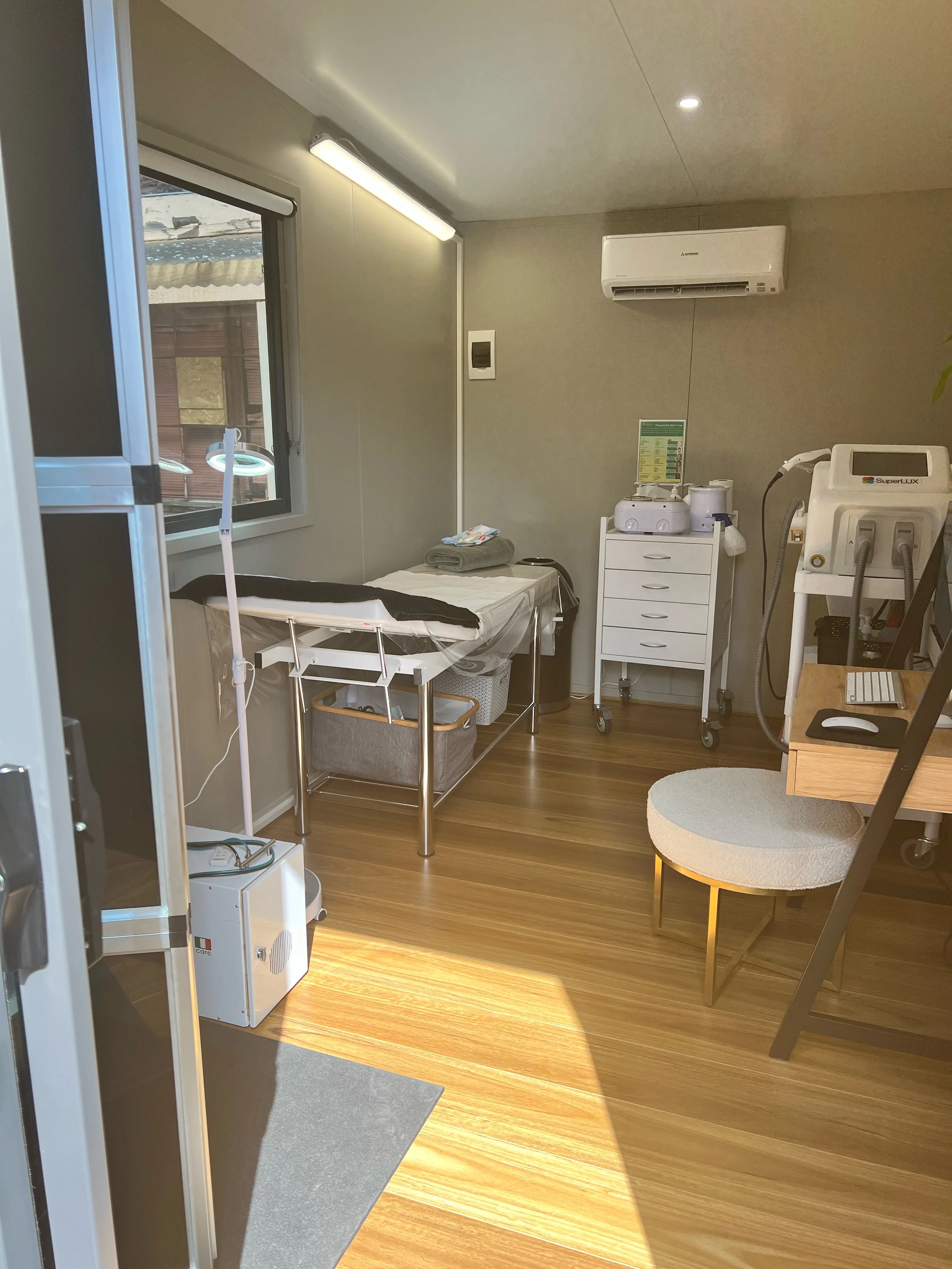 Wider view of the Vanish treatment room — timber floor, bed and trolley