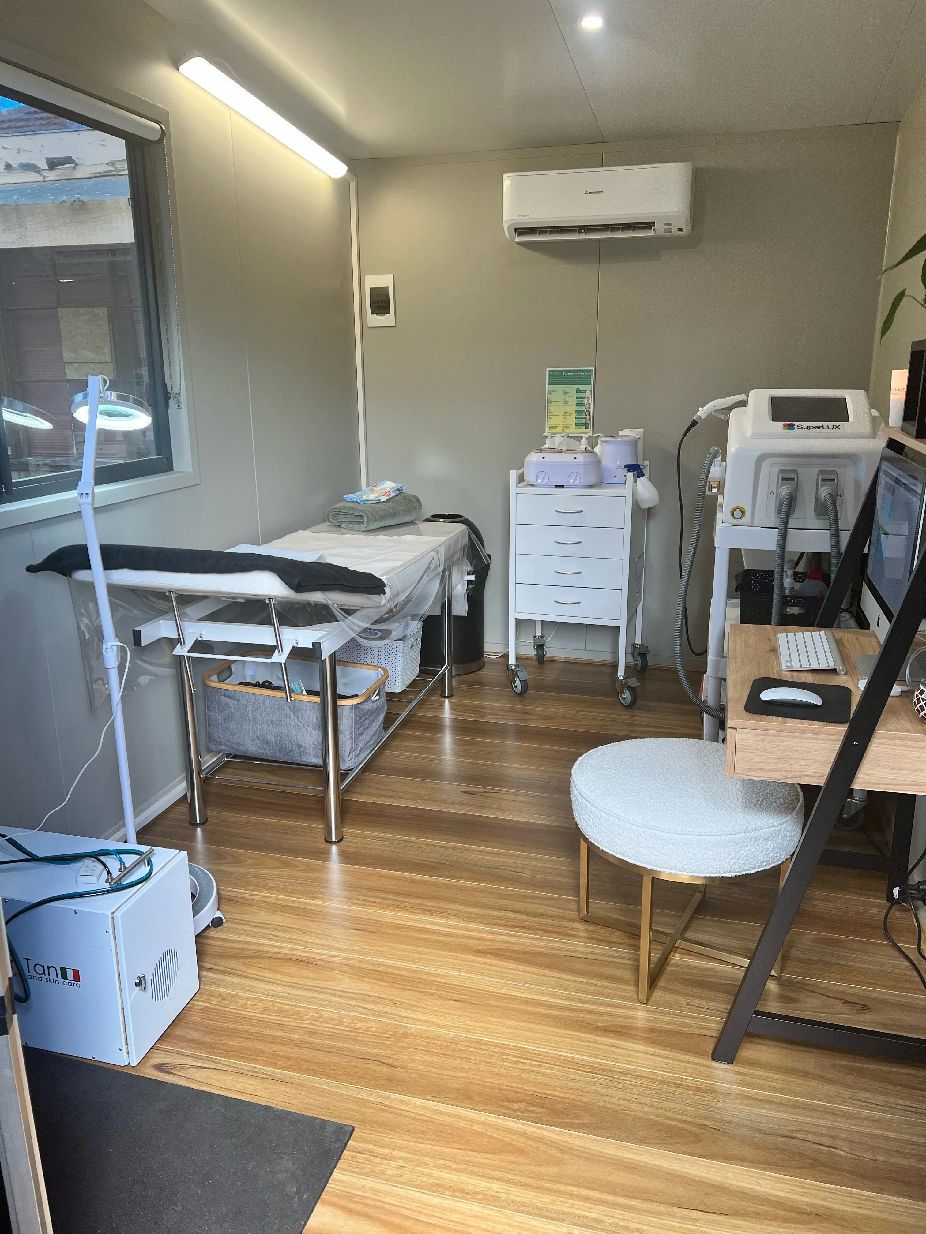 Treatment bed, magnifying lamp and Fitzpatrick skin-type chart on the wall