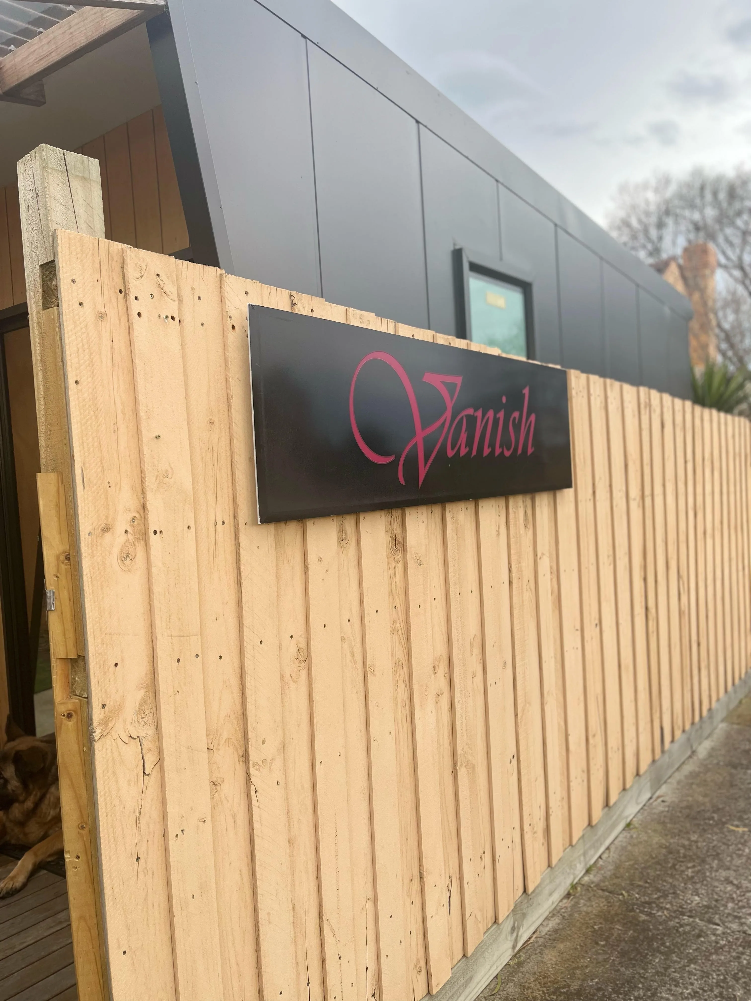 The black Vanish signboard on the timber privacy fence at the studio entrance