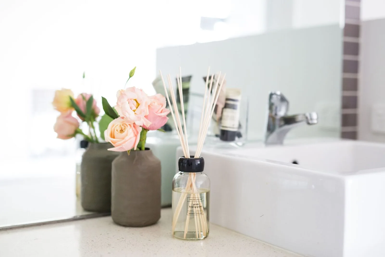 Abode Aroma Pink Frangipani diffuser and fresh roses on the studio vanity