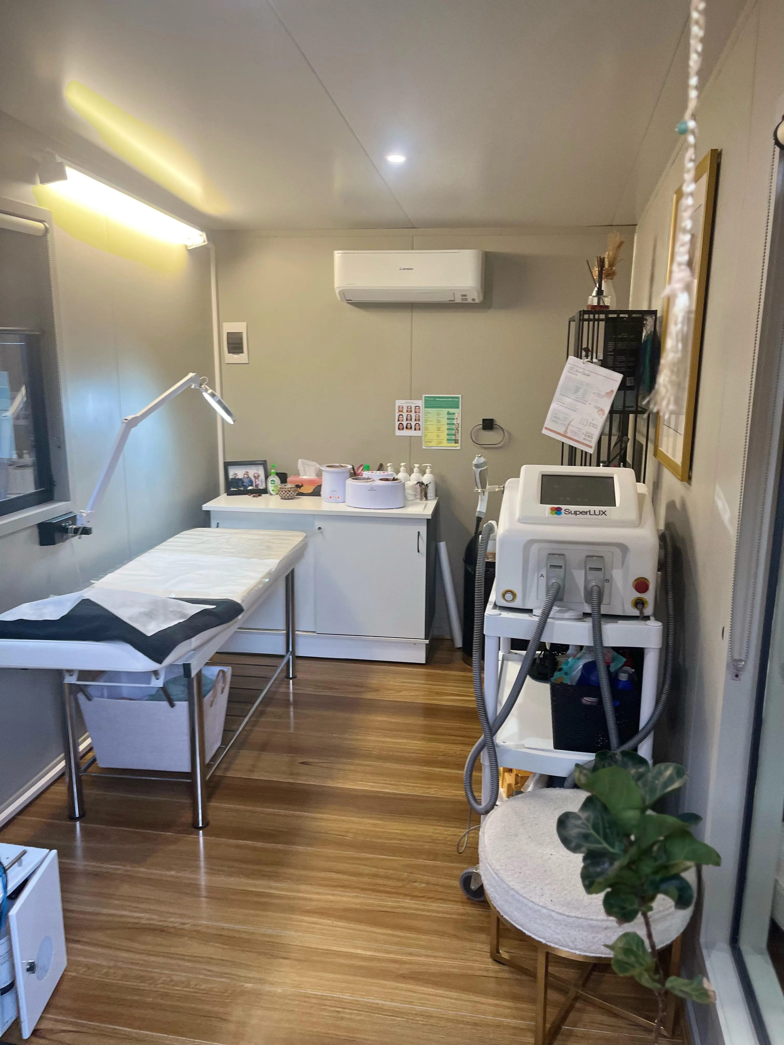 Vanish treatment room — bed, wax warmers, SuperLUX IPL unit and warm natural light